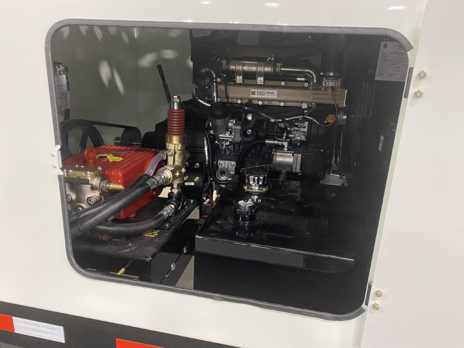 Open compartment showing O'Brien Sewer Jetters power pack with Kohler engine and red high‑pressure jetter pump.