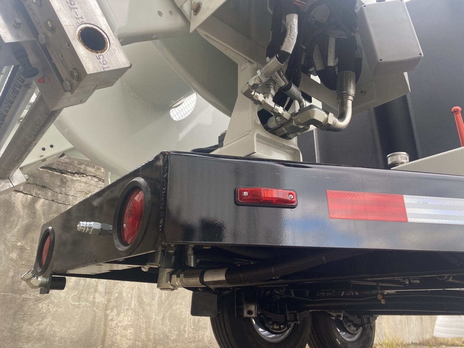 Close-up of O'Brien Sewer Jetters trailer frame showing hydraulic lines, taillights, and reel mount.