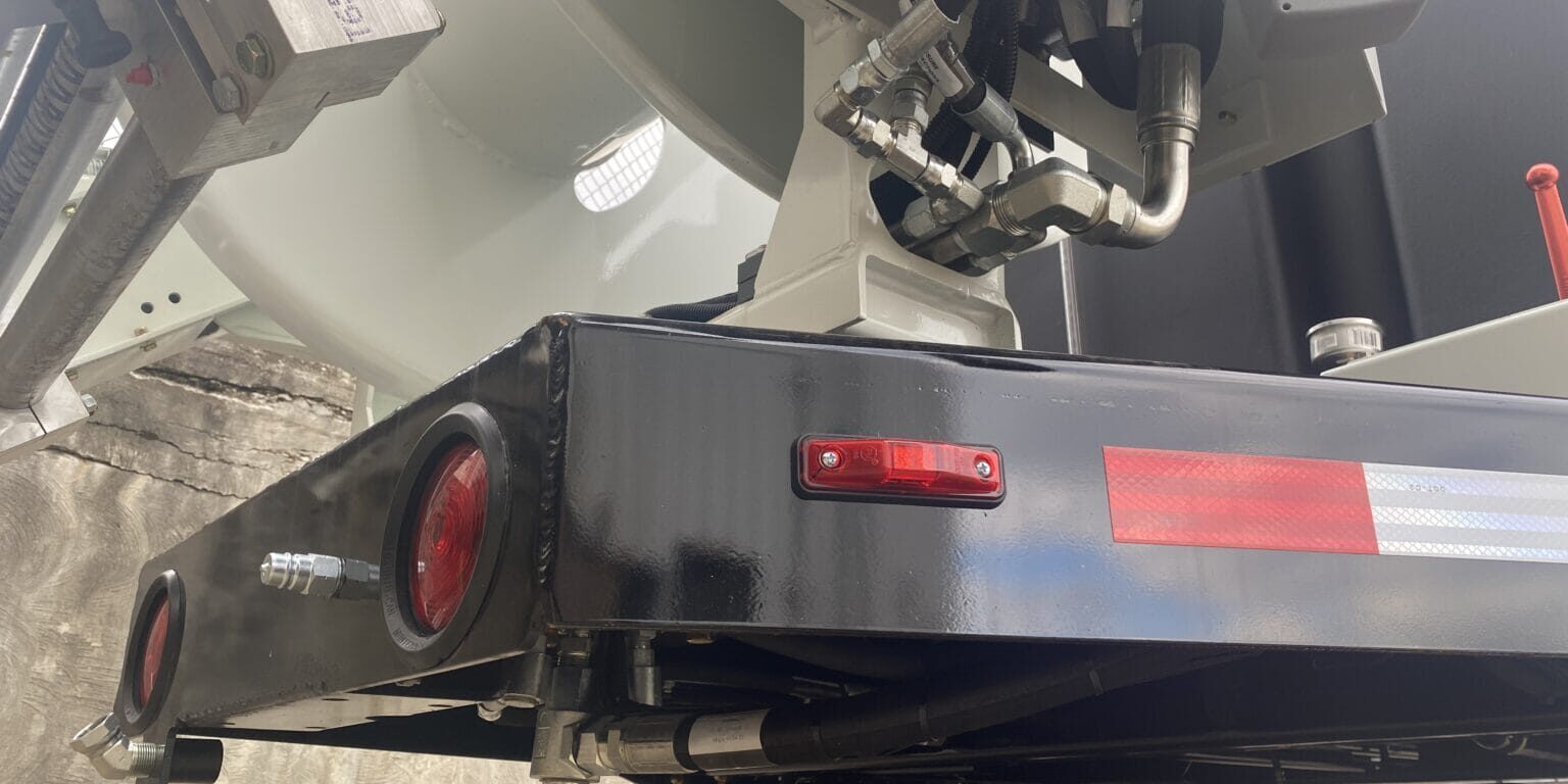 Close-up of O'Brien Sewer Jetters trailer frame showing hydraulic lines, taillights, and reel mount.